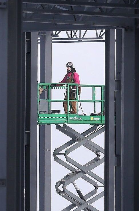  a worker is sandwiched between steel beams at the construction site of a new industrial plant on county road 42 east of windsor airport on tuesday, feb. 11, 2025.