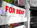 A white and red sign advertises a house for rent.