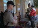 A home inspector stands by while landlord Eslin Payne and her daughter, Natasha, talk with a tenant on the porch of their Hall Avenue home on Oct. 26, 2024, in a dispute over months of unpaid rent. Payne and her daughter drove from Toronto to inspect the house after giving written notice, but the tenants refused to let them in.