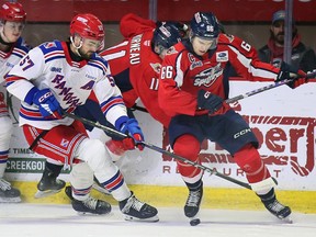 The Kitchener Rangers' Trent Swick, left, and Windsor Spitfires' captain Liam Greentree battle for the puck during Thursday's game.
