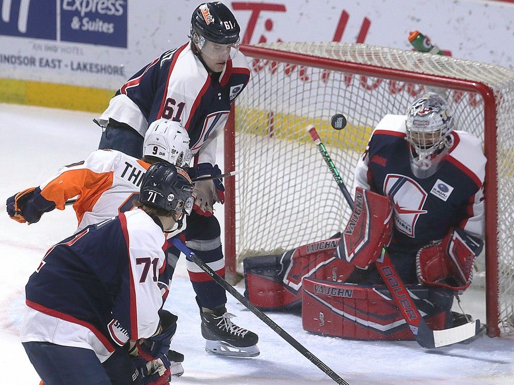Windsor Spitfires' goalie Joey Costanzo makes a save on Flint Firebird Christopher Thibodeau as Jack Nesbitt, below, and Ethan Belchetz close in on Friday.