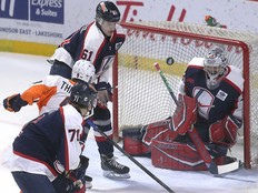 Windsor Spitfires' goalie Joey Costanzo makes a save on Flint Firebird Christopher Thibodeau as Jack Nesbitt, below, and Ethan Belchetz close in on Friday.