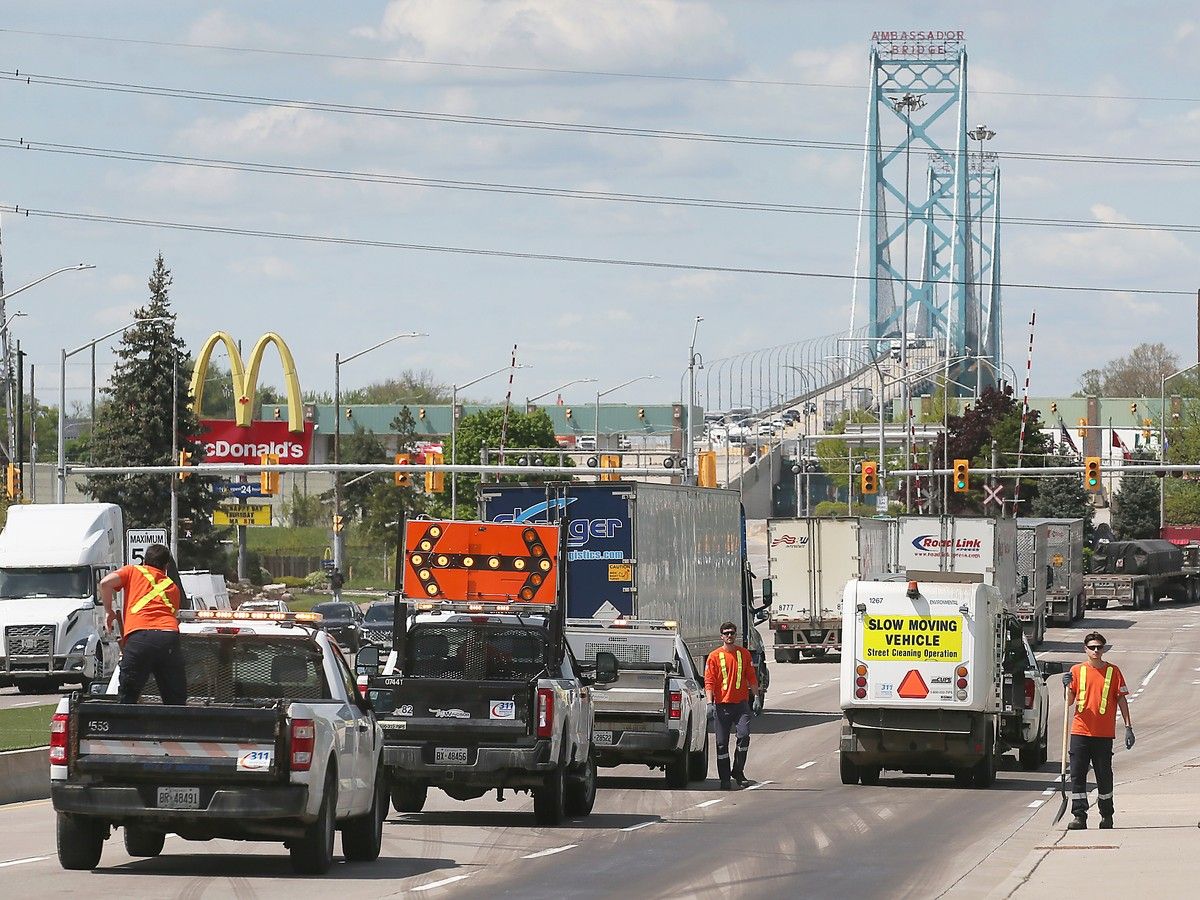  City workers help clean up a multi-vehicle accident on Huron Church Road near Girardot Street in Windsor on May 7, 2025, with the Ambassador Bridge looming in the background.