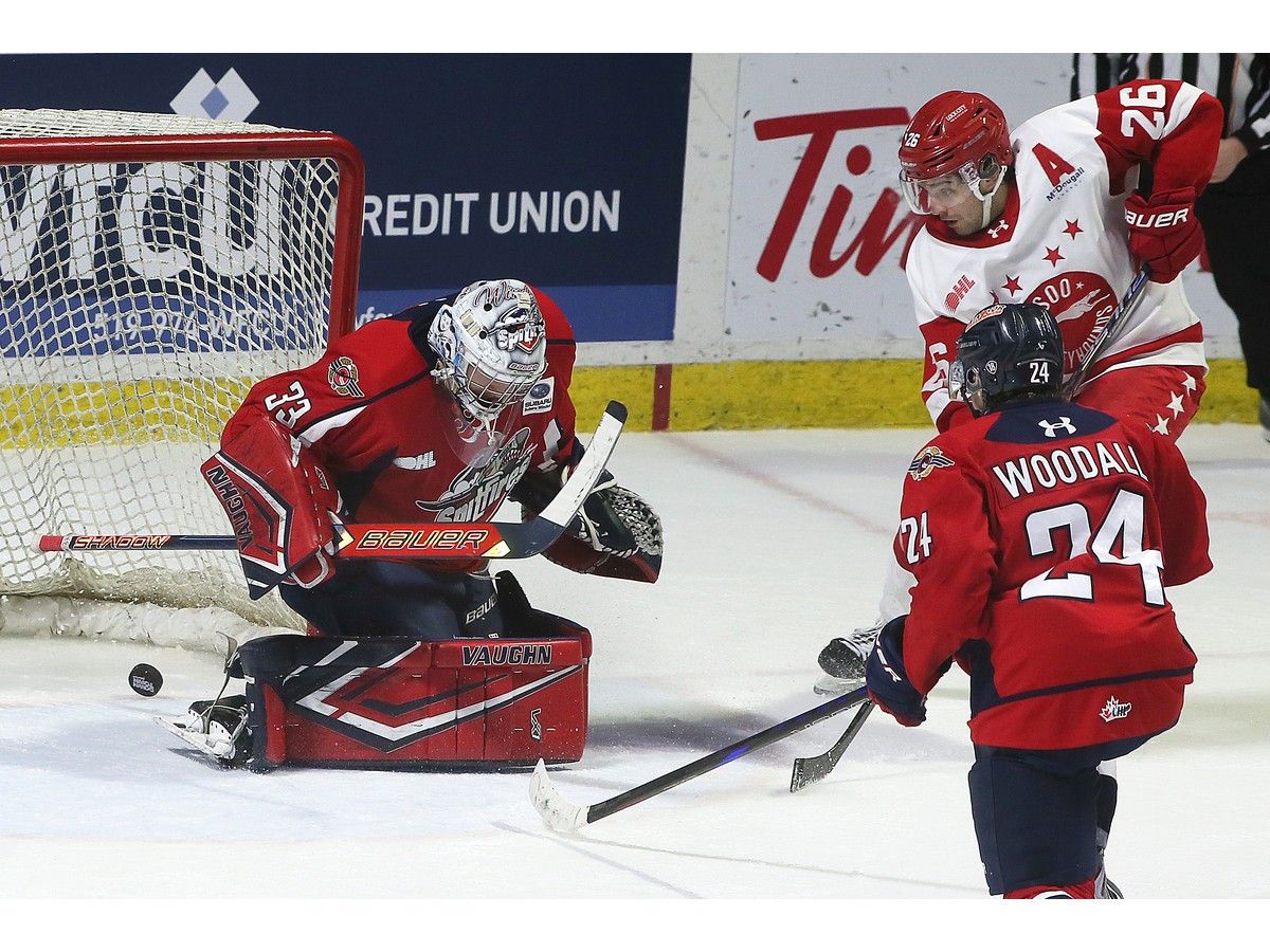 Sault Ste. Marie Greyhounds's forward Marco Mignosa scores the game-winning goal in overtime on Windsor Spitfires' goalie Joey Costanzo as teammate Carson Woodall looks on at the WFCU Centre on Thursday.