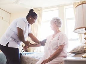 A nurse checks the blood pressure of senior female patient.