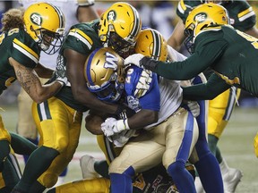 Winnipeg Blue Bombers' Timothy Flanders (20) is tackled by the Edmonton Eskimos during second half CFL action in Edmonton, Alta., on Saturday September 30, 2017. THE CANADIAN PRESS/Jason Franson