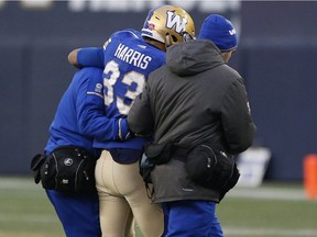 Winnipeg Blue Bombers' Andrew Harris (33) is helped off the field after getting hit by Dyshawn Davis of the B.C. Lions on Saturday.
