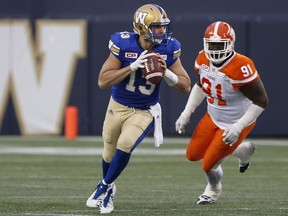 Winnipeg Blue Bombers' quarterback Dan LeFevour (13) is pursued by BC Lions' Junior Luke (91) during Saturday's action in Winnipeg.