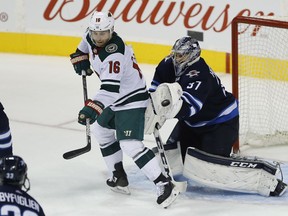 Jets goaltender Connor Hellebuyck (37) stops the deflection by Minnesota Wild's Jason Zucker (16) during NHL action in Winnipeg earlier this month.