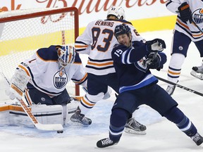 Winnipeg Jets' Matt Hendricks (15) attempts to get the rebound off Edmonton Oilers goaltender Laurent Brossoit (1) as Matthew Benning (83) defends during first period NHL pre-season game action in Winnipeg on Wednesday, September 20, 2017. THE CANADIAN PRESS/John Woods ORG XMIT: JGW103