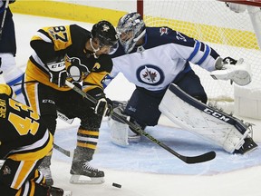 Pittsburgh Penguins' Sidney Crosby (87) can't get his stick on a rebound in front of Winnipeg Jets goalie Connor Hellebuyck (37) in the first period Thursday in Pittsburgh.