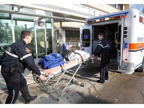Paramedics load a stretcher into an ambulance.