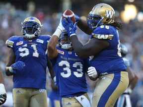 Winnipeg Blue Bombers OL Travis Bond (right) grabs the ball from Andrew Harris after his touchdown run during CFL action against the Toronto Argonauts in Winnipeg on Thurs., July 13, 2017. Kevin King/Winnipeg Sun/Postmedia Network