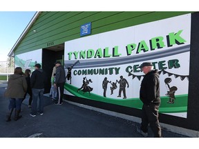 People head back indoors to escape the cold wind soon after the unveiling of a new mural at the Tyndall Park Community Centre on King Edward Street in Winnipeg on Sunday.