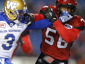 Winnipeg Blue Bombers Kevin Fogg, left, grabs Calgary Stampeders Jameer Thurman helmet during CFL action at McMahon Stadium in Calgary on Friday. (Leah hennel/Postmedia)