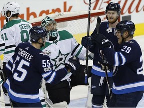 Winnipeg Jets' Mark Scheifele (55), Kyle Connor (81) and Patrik Laine (29) celebrate Scheifele's goal against Dallas Stars in Winnipeg on Thursday.