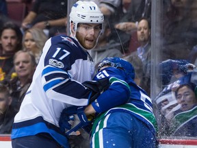 Winnipeg Jets' Adam Lowry, left, checks Vancouver Canucks' Troy Stecher during the first period of an NHL hockey game in Vancouver, B.C., on Thursday October 12, 2017. THE CANADIAN PRESS/Darryl Dyck ORG XMIT: VCRD106 ORG XMIT: POS1710122159090098