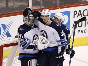 Winnipeg Jets goalie Steve Mason (35) celebrates a win against the Arizona Coyotes with Jets defenseman Tyler Myers (57) and defenseman Dmitry Kulikov (5) after the third period of an NHL hockey game Saturday, Nov. 11, 2017, in Glendale, Ariz. The Jets defeated the Coyotes 4-1. (AP Photo/Ross D. Franklin) ORG XMIT: PNJ117
Ross D. Franklin, AP