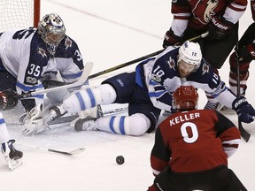 Winnipeg Jets center Bryan Little (18) slides in to help make a save with goalie Jets goalie Steve Mason (35) on a shot by Arizona Coyotes center Clayton Keller (9) during Saturday's game.