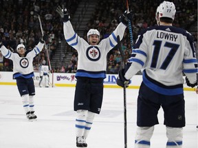 Winnipeg Jets defenceman Dmitry Kulikov (center) celebrates after assisting on a goal by Adam Lowry (17) against the Vegas Golden Knights during the first period Friday.