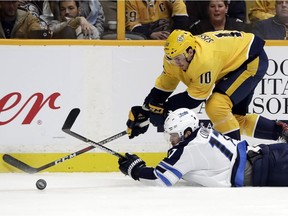 Winnipeg Jets center Adam Lowry (17) falls as he chases the puck with Nashville Predators center Colton Sissons (10) in NHL action, Monday in Nashville.