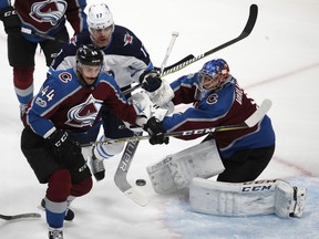 Colorado Avalanche defenseman Mark Barberio, left, pursues the puck after Winnipeg Jets center Adam Lowry, center, had his shot stopped by Avalanche goalie Semyon Varlamov, of Russia, in the first period of an NHL hockey game Wednesday, Nov. 29, 2017, in Denver. (AP Photo/David Zalubowski) ORG XMIT: CODZ103