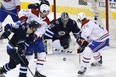 Jets goaltender Connor Hellebuyck tries to stop Montreal’s Phillip Danault (centre left) and Jeff Petry as they storm the net.