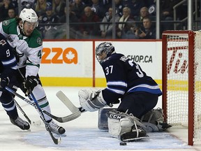 Jets centre Andrew Copp (left) ties up Stars forward Remi Elie in front of goalie Connor Hellebuyck last night. (Kevin King/Winnipeg Sun)