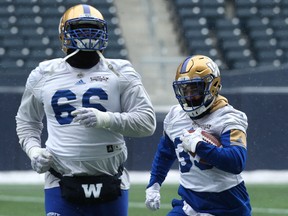 Running back Andrew Harris (right) carries the ball behind offensive tackle Stanley Bryant during Winnipeg Blue Bombers practice in Winnipeg on Wednesday.