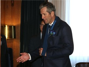 Premier Brian Pallister extends one hand, with the other in a sling, prior to the opening of a new session with the throne speech at the Manitoba Legislative Building on Tuesday.
