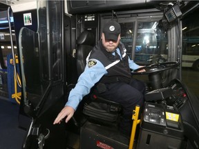 A bus operator sits in the driver's seat of a transit bus, at the unveiling event for a shield intended to improve the safety of bus drivers, last November.
