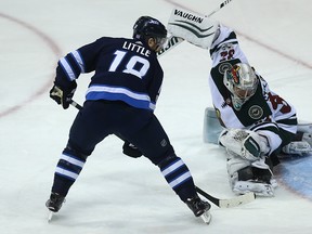 Winnipeg Jets centre Bryan Little tips a puck past Minnesota Wild goaltender Alex Stalock on Monday. (Kevin King/Winnipeg Sun/Postmedia Network)