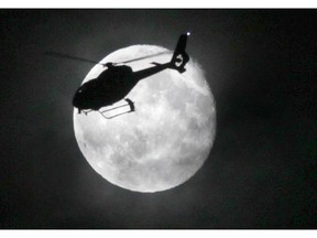 The police helicopter flies past the full moon over Winnipeg.  Saturday, April 27, 2013.