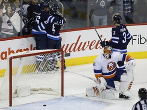 Winnipeg Jets' Blake Wheeler, Kyle Connor, Patrik Laine and Tucker Poolman (right) celebrate a goal as New York Islanders goalie Jaroslav Halak looks on during Friday night's game. (THE CANADIAN PRESS)