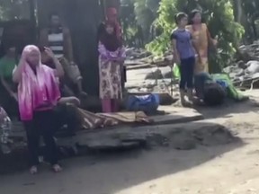 In this image made from video, people stand while injured on the ground after a flash flood in Lanao del Norte, Mindanao, southern Philippines, Sunday, Dec. 24, 2017. (AP Photo)