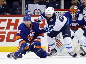 Johnny Boychuk (55) of the New York Islanders and Mathieu Perreault (85) of the Winnipeg Jets battle for the puck Saturday.