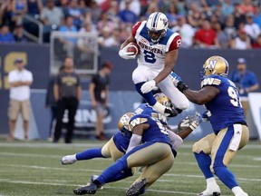 Montreal Alouettes slotback Nik Lewis (8) hurdles Winnipeg Blue Bombers linebacker Kyle Knox (50) and defensive lineman Jamaal Westerman (55) before being tackled by defensive tackle Drake Nevis (92) during the first half of CFL football action in Winnipeg on Thursday, July 27, 2017. THE CANADIAN PRESS/Trevor Hagan ORG XMIT: WPGT102 ORG XMIT: POS1707272126274543 ORG XMIT: POS1707272136594566