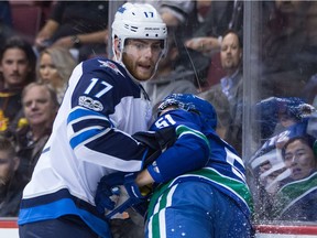 Winnipeg Jets' Adam Lowry, left, checks Vancouver Canucks' Troy Stecher during the first period of an NHL hockey game in Vancouver, B.C., on Thursday October 12, 2017.