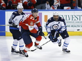 Florida Panthers center Nick Bjugstad (27) and Winnipeg Jets defenseman Dustin Byfuglien (33) and center Mark Scheifele (55) compete for the puck during the second period of an NHL hockey game Thursday, Dec. 7, 2017, in Sunrise, Fla. (AP Photo/Wilfredo Lee) ORG XMIT: FLWL109