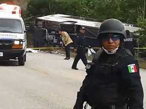 Video grab of Mexican police officers standing guard in the area where a bus driving tourists to Chacchoben archaeological zone overturned in the road between El Cafetal and Mahahual, in Quintana Roo state, Mexico on December 19, 2017. (EMANUEL JESUS ORTEGA CANCHE/AFP/Getty Images)