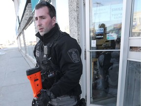 A Winnipeg Police officer walks away from a business on Main Street.  An individual inside the business was in apparent medical distress.  Saturday, December 02, 2017.   Sun/Postmedia Network