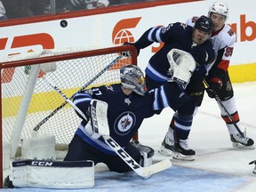 Jets goaltender Connor Hellebuyck gets enough of a shot from the Senators to send it out of play last night.  (Kevin King/Winnipeg Sun)