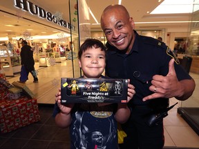 Jason brings a present in to be wrapped with a Winnipeg Poilce Service member during the 11th annual Cop Shop event at St. Vital Centre in Winnipeg on Wed., Dec. 6, 2017. Kevin King/Winnipeg Sun/Postmedia Network