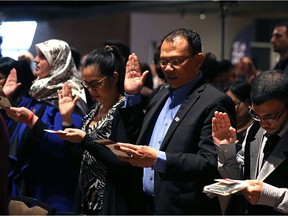 People take the citizenship oath during a special citizenship ceremony at the Canadian Museum of Human Rights in Winnipeg on Sun., Dec. 10, 2017. Kevin King/Winnipeg Sun/Postmedia Network