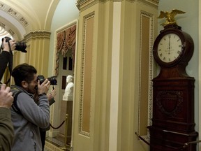 Photographers take a picture of the Ohio Clock shortly after midnight early Saturday, Jan. 20, 2018, outside the Senate chamber at the Capitol in Washington. The federal government shut down at midnight, halting all but the most essential operations.