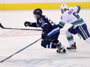 Winnipeg Jets' Jack Roslovic (52) and Vancouver Canucks' Brock Boeser (6) chase the puck NHL hockey in Winnipeg, Sunday.