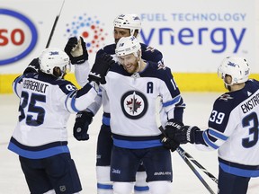 Winnipeg Jets' Bryan Little (18) celebrates a goal with teammates Mathieu Perreault (85), Dustin Byfuglien (33) and Toby Enstrom (39) during the game against the Calgary Flames in Calgary Saturday.