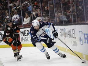 Winnipeg Jets' Blake Wheeler, right, moves the puck past Anaheim Ducks' Ryan Getzlaf during the first period of an NHL hockey game Thursday, Jan. 25, 2018, in Anaheim, Calif.