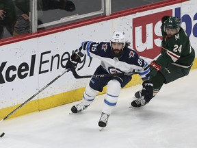 Winnipeg Jets' Mathieu Perreault (85) controls the puck in front of Minnesota Wild's Matt Dumba (24) in the first period Saturday in St. Paul, Minn.