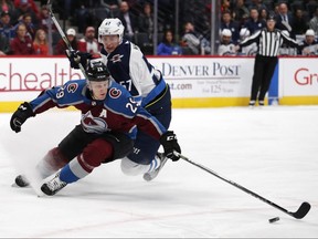 Colorado Avalanche centre Nathan MacKinnon (front) fights for the puck with Winnipeg Jets defenceman Tyler Myers. (AP)